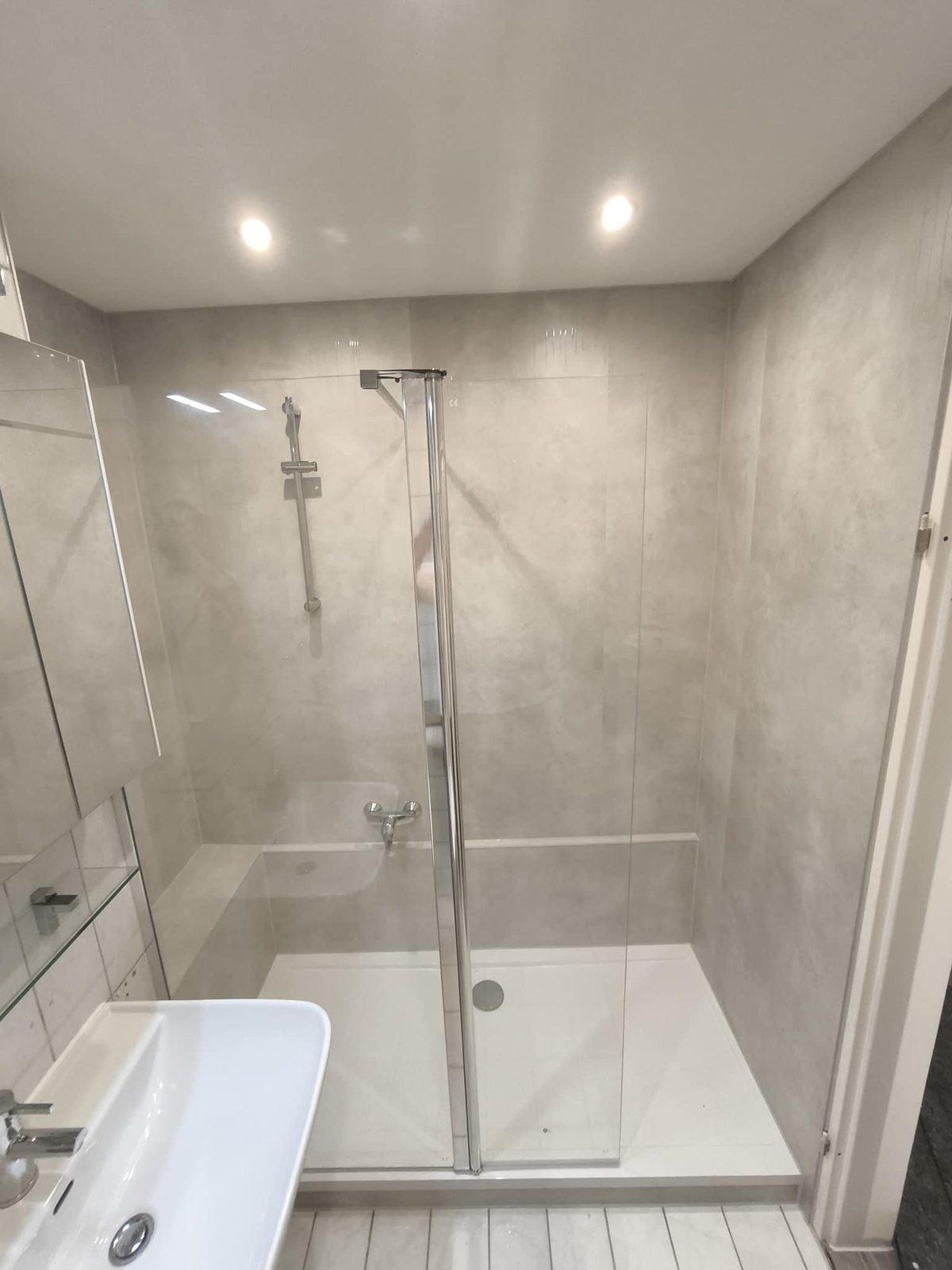 Nachher: dasselbe Bad mit Dusche, Glaswand und neuen Wandpaneelen