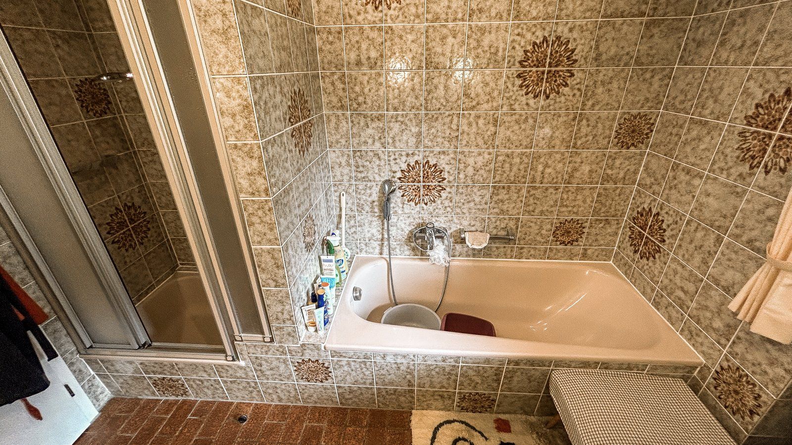 Vorher: Badewanne und enge Duschkabine, gemusterte Fliesen